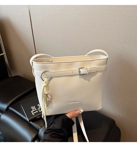Detail of white lychee pattern bucket bag with silver heart charm and buckle strap