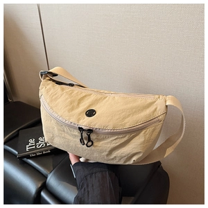 Detail of beige nylon crescent crossbody bag with black zipper and adjustable wide strap