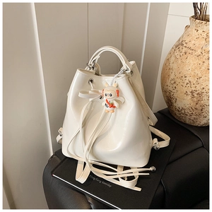 Detail of white patent leather bucket backpack with drawstring and cute bunny charm