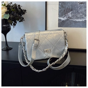 Detail of silver quilted crossbody bag with metallic chain strap and turn-lock closure