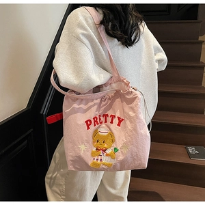 Detailed embroidery of a bear and PRETTY text on a pink drawstring nylon tote bag