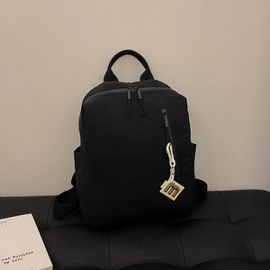 Detail of black nylon backpack with vertical zipper pocket and square m-logo charm