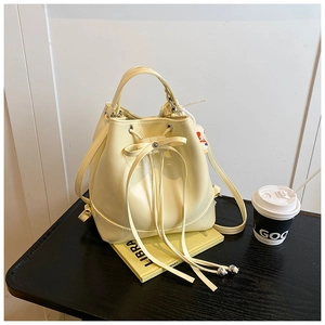 Detail of creamy yellow bucket bag with drawstring closure and stylish bow decoration