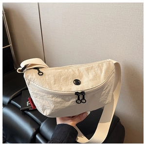 Detail view of the cream nylon crossbody bag featuring crinkled texture and black zippers