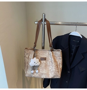 Detail of floral tote bag featuring leather handles and cute plush cloud charm