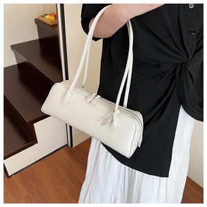 Close-up of cream white cylindrical baguette bag with sleek dual zipper closure details