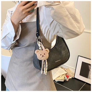 Close-up of a charcoal crescent hobo bag with a plush bear charm and white logo detail