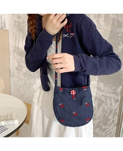 Détail du sac bandoulière bleu marine avec cerises brodées et bouton à carreaux rouges