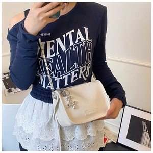 Detail of white crossbody bag with chain strap and silver balloon dog pendant