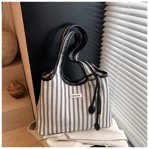 Detail of striped canvas tote bag with black leather trim and COIH'DN2 brand tag on fabric