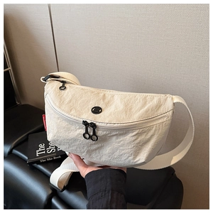Detail of cream nylon crossbody bag showing crinkled texture and dual zipper closure