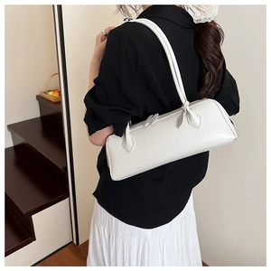 Close-up of a white cylindrical baguette bag with sleek shoulder straps and silver zippers