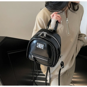 Close-up of a glossy black mini backpack featuring silver metal hardware and smooth finish