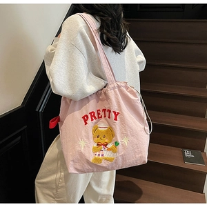 Detail of pink canvas tote bag featuring cute yellow bear embroidery and PRETTY text