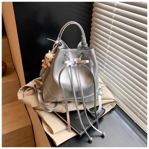 Detail of silver bucket bag showing glossy texture, drawstring bow, and cartoon sheep charm