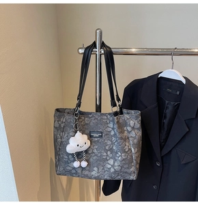 Detail of dark grey floral tote bag with black leather handles and cute cloud plush charm