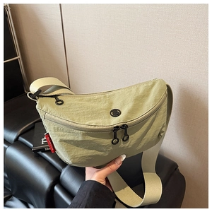 Detail of light green nylon crescent bag with double zippers and brand woven label