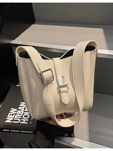 Sac seau classique en cuir crème avec boucle métallique sur des escaliers urbains