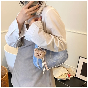 Close-up of blue denim underarm bag with silver trim and cute plush bear charm