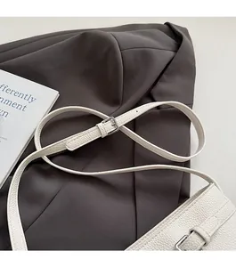 Detail of white litchi leather bucket bag with adjustable strap and silver metal buckle