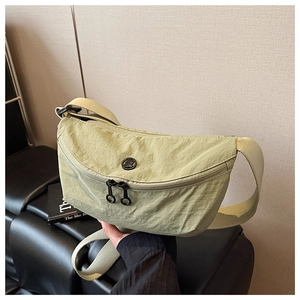 Close-up of pistachio green crescent nylon bag with dual zippers and round metal logo