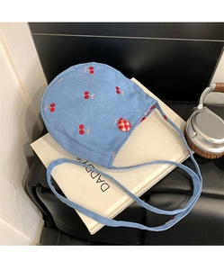 Détail d'un petit sac en jean bleu clair avec broderies cerises et fermeture à bouton