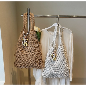 Detail of hollow woven tote bag with mesh design, pearl chain and cartoon pendant