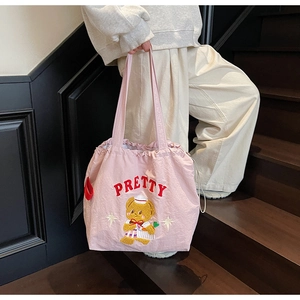 Close-up of pink canvas tote bag with Pretty bear embroidery and red drawstring detail