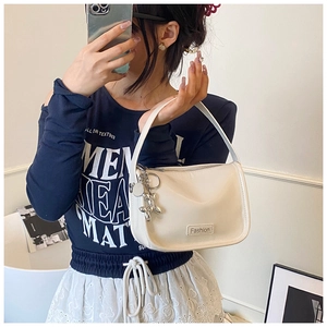 Close-up of white minimalist crossbody bag with silver balloon dog charm and zip closure