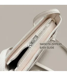 Detail of smooth silver metal zipper on white lychee grain leather bucket bag