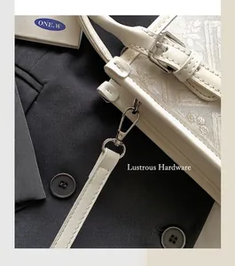 Gros plan d'un sac bandoulière brodé géométrique avec des boucles en métal argenté