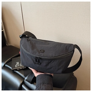 Macro view of black nylon crossbody bag with double zipper and small brand logo
