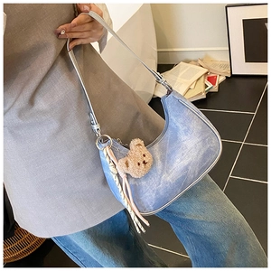 Blue denim crescent underarm bag with silver strap and brown plush bear charm detail