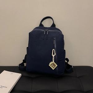 Detail of dark blue nylon backpack with vertical zipper and yellow M letter charm