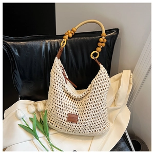 Detail of hand-woven hollow knit tote featuring wooden beads and leather logo patch