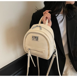 Detail of glossy beige leather mini backpack with dual zippers and silver metallic plate
