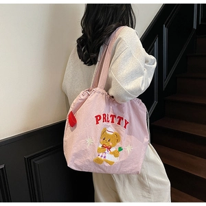 Detail of pink tote bag with PRETTY lettering, cartoon bear embroidery and drawstring closure