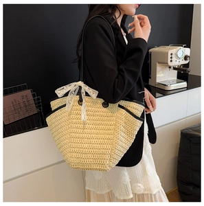 Détail du sac cabas en paille beige avec nœud en dentelle blanche et bordure en cuir noir
