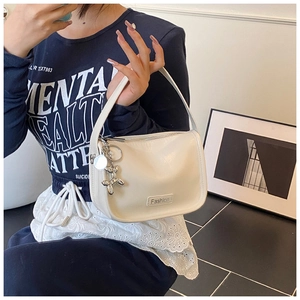 Detail of cream leather handbag with silver balloon dog charm and metal brand plate