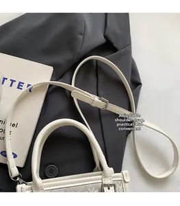 Détail d'un sac bohème avec bandoulière réglable posé sur une veste de blazer grise