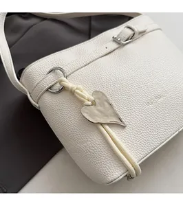 Detail of white lychee leather bucket bag with silver heart charm and rope detail