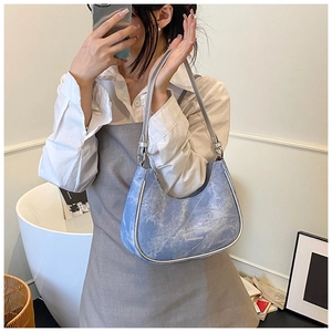 Mirror selfie showing the light blue washed texture crescent bag with silver trim details