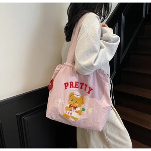 Detail of pink drawstring tote bag featuring pretty letter and cartoon bear embroidery