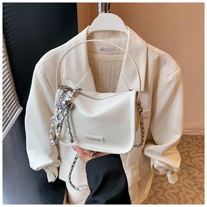 Detail of white glossy crossbody bag with silver chain strap and metal ball charm