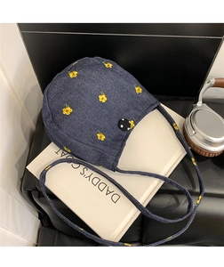 Gros plan détaillé d'un sac bandoulière en denim bleu avec broderie florale jaune fine