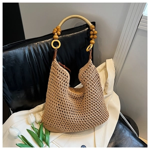 Close-up of woven straw tote bag with gold ring handle and wooden beads decoration