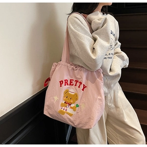 Close-up of pink tote bag featuring cute teddy bear embroidery and drawstring closure