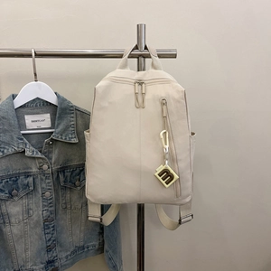 Detail of off-white nylon backpack with functional side pockets and decorative m-pendant