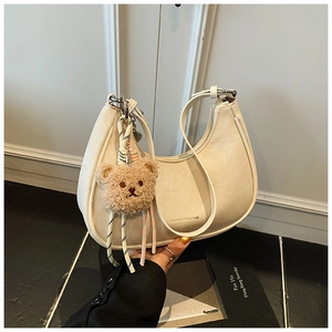 Detail of off-white crescent crossbody bag with cute plush bear charm and zip closure