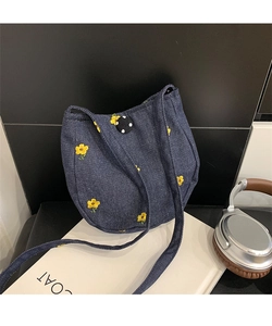 Détail du sac bandoulière en denim bleu avec broderies florales jaunes et bords festonnés